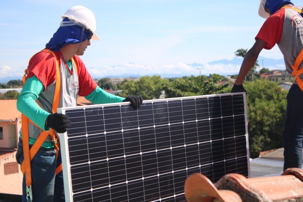 Instaladores segurando um painel fotovoltaico durante uma instalação